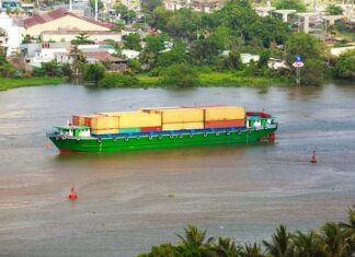 Канада и Испания подписали меморандум о «зелёном морском коридоре» Colorful container ship sailing on a river near a small town, view from above.