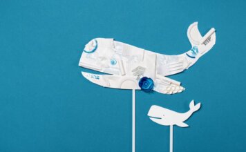 Conceptual image of a whale shape made from recycled plastic on a bright blue background.