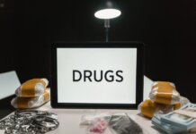 Conceptual image of drugs, money, and handcuffs on a table under harsh light, depicting crime themes.