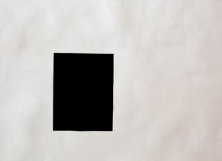 Creative black mock up rectangular paper sheet with copy space attached on white wall in light room of modern studio
