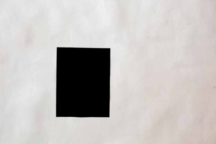 Creative black mock up rectangular paper sheet with copy space attached on white wall in light room of modern studio Creative black mock up rectangular paper sheet with copy space attached on white wall in light room of modern studio