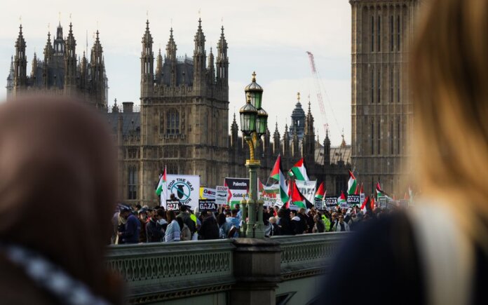 Crowd protesting on Westminster Bridge, London against Gaza conflict, waving Palestinian flags. Crowd protesting on Westminster Bridge, London against Gaza conflict, waving Palestinian flags.