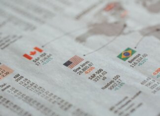 Detailed close-up of a newspaper displaying global financial market statistics and country flags.