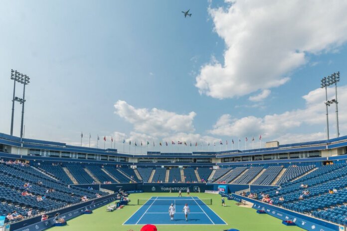 Dynamic tennis match in progress at an outdoor stadium in Toronto 2015 event, with vibrant sky and audience. Dynamic tennis match in progress at an outdoor stadium in Toronto 2015 event, with vibrant sky and audience.