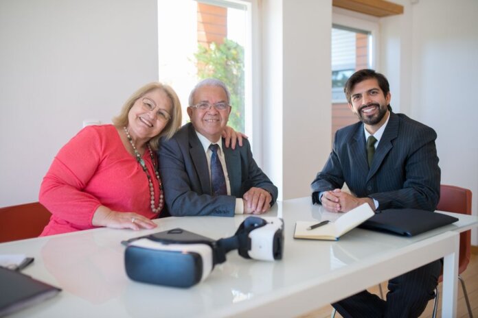 Elderly couple smiling with real estate agent during home meeting, showcasing modern technology. Elderly couple smiling with real estate agent during home meeting, showcasing modern technology.