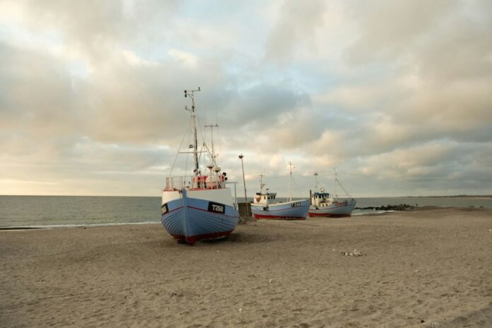 Fishing boats anchored on the sandy shores of Thisted, Denmark during a calm sunset. Fishing boats anchored on the sandy shores of Thisted, Denmark during a calm sunset.
