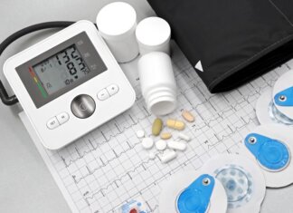 Flat lay of blood pressure monitor, pills, and ECG printout for heart health theme.