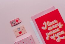 Flat lay of romantic cards and envelopes with love messages on a soft pink background.