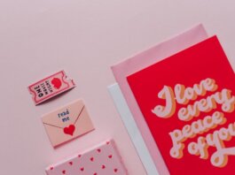 Flat lay of romantic cards and envelopes with love messages on a soft pink background.