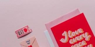 Flat lay of romantic cards and envelopes with love messages on a soft pink background.