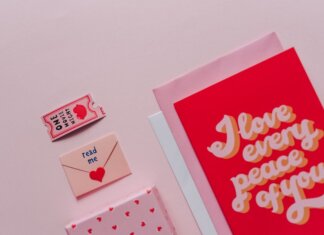 Flat lay of romantic cards and envelopes with love messages on a soft pink background.