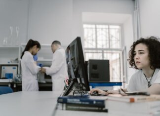 Исследователи Университета Западного Онтарио получили $19 млн грантов Focused woman working on a computer in a busy laboratory setting, showcasing teamwork and scientific research.