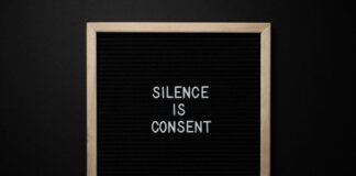 From above blackboard with written phrase SILENCE IS CONSENT on center on black background