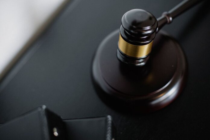 From above of wooden gavel on round surface near folders on table in courtroom From above of wooden gavel on round surface near folders on table in courtroom
