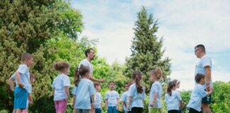 Group of children and teachers playing and learning in a sunny park setting.