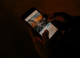 В Квебеке расширят мобильную связь для безопасности жителей Hands holding a smartphone browsing social media in low light.
