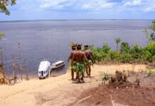 Береговая охрана выделила $1,6 млн коренным общинам на лодки Indigenous men in traditional attire overlooking boats on the Amazon River.