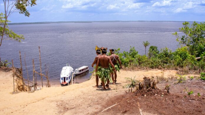 Indigenous men in traditional attire overlooking boats on the Amazon River. Indigenous men in traditional attire overlooking boats on the Amazon River.