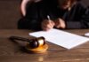 В Верховный суд Британской Колумбии назначен новый ассоциированный судья Judge signing documents at desk with focus on gavel, representing law and justice.