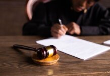 В Верховный суд Британской Колумбии назначен новый ассоциированный судья Judge signing documents at desk with focus on gavel, representing law and justice.