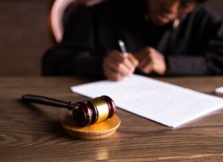 В Верховный суд Британской Колумбии назначен новый ассоциированный судья Judge signing documents at desk with focus on gavel, representing law and justice.