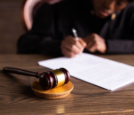 Judge signing documents at desk with focus on gavel, representing law and justice.