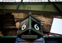 Low angle view of a vintage Track 6 sign at a railway station, showcasing rustic industrial architecture.