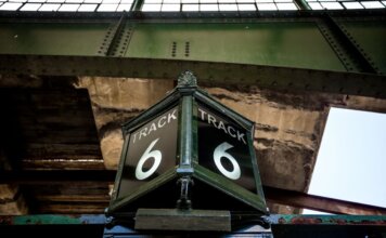 Шесть способов, как приложение Transit упрощает поездки по Ванкуверу Low angle view of a vintage Track 6 sign at a railway station, showcasing rustic industrial architecture.