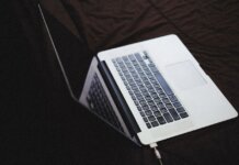 Инспектор по условно-досрочному освобождению обвинена в злоупотреблении доверием Modern laptop with backlit keyboard on a dark fabric surface, connected to a charger.