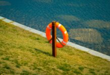 Как не утонуть в Великих озёрах: советы экспертов из Ватерлоо Orange lifebuoy hangs on a wooden post by a calm lake, symbolizing safety and preparedness.