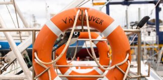 Orange lifebuoy labeled 'Vancouver' on a docked boat, ready for safety and rescue.