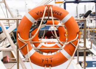 Orange lifebuoy labeled 'Vancouver' on a docked boat, ready for safety and rescue.