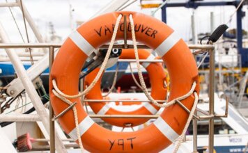 Канада вводит защитные пошлины на импорт консервированных овощей Orange lifebuoy labeled 'Vancouver' on a docked boat, ready for safety and rescue.