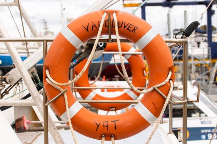 Orange lifebuoy labeled 'Vancouver' on a docked boat, ready for safety and rescue. Orange lifebuoy labeled 'Vancouver' on a docked boat, ready for safety and rescue.