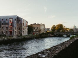Picturesque view of the river in Galway, Ireland at sunset with historic buildings and a charming bridge.