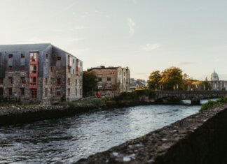 Picturesque view of the river in Galway, Ireland at sunset with historic buildings and a charming bridge.