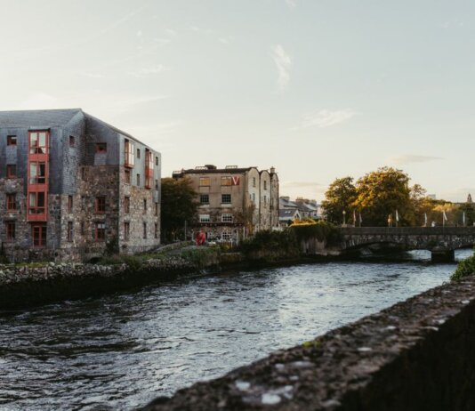 Picturesque view of the river in Galway, Ireland at sunset with historic buildings and a charming bridge.