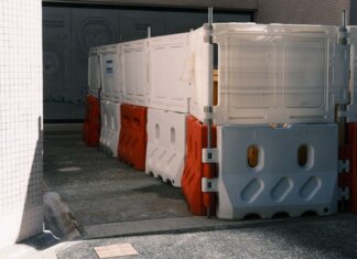 Plastic roadblock barriers with red and white colors in an urban area.