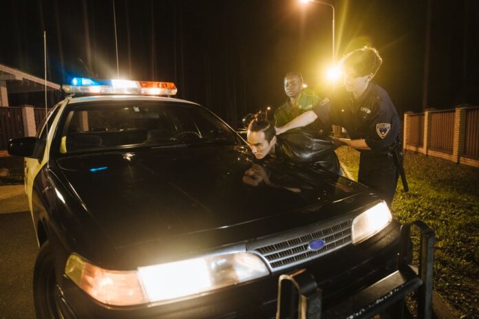 Police officers apprehending a suspect at night under streetlights by a patrol car. Police officers apprehending a suspect at night under streetlights by a patrol car.