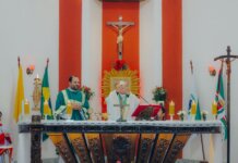 Priests conducting a Catholic mass ceremony in a church with religious artifacts and crosses.