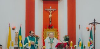 Priests conducting a Catholic mass ceremony in a church with religious artifacts and crosses.