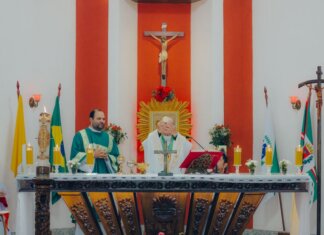 Priests conducting a Catholic mass ceremony in a church with religious artifacts and crosses.