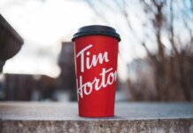 Red Tim Horton coffee cup placed on a concrete surface with a blurred outdoor background.