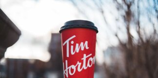 Red Tim Horton coffee cup placed on a concrete surface with a blurred outdoor background.