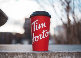 Пять главных итогов вдохновляющего выступления Канады на ЧМ-2026 Red Tim Horton coffee cup placed on a concrete surface with a blurred outdoor background.