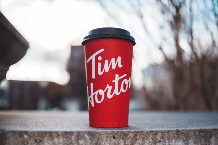 Red Tim Horton coffee cup placed on a concrete surface with a blurred outdoor background. Red Tim Horton coffee cup placed on a concrete surface with a blurred outdoor background.
