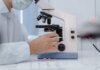 Researcher analyzing samples with a microscope in a lab setting.