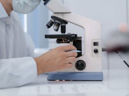 Researcher analyzing samples with a microscope in a lab setting.