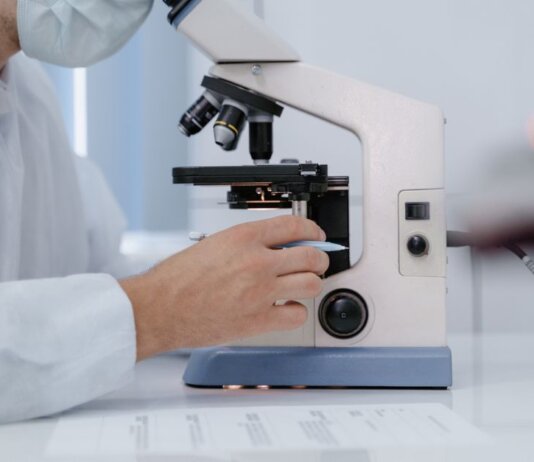 Researcher analyzing samples with a microscope in a lab setting.
