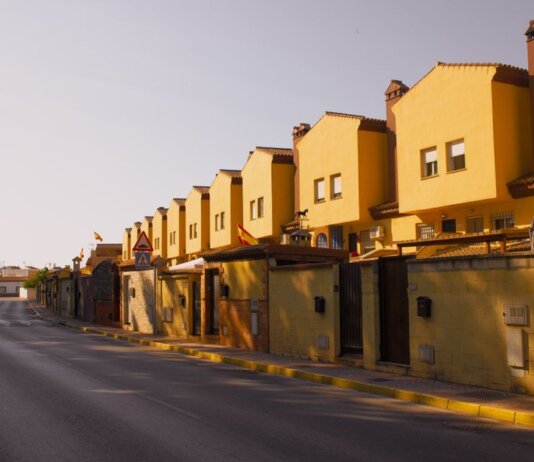 Row of yellow suburban houses under warm evening light, showcasing Mediterranean architecture.